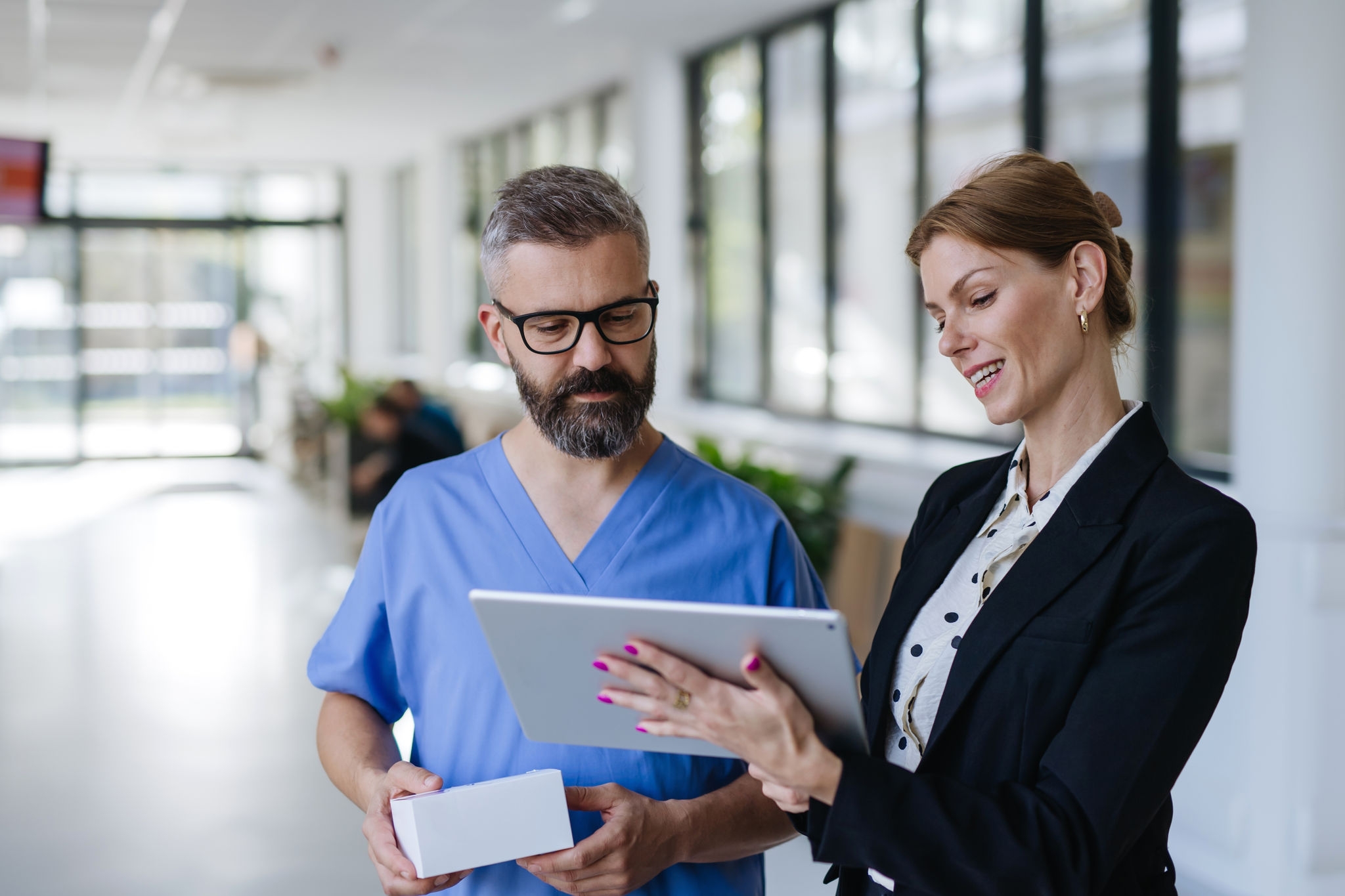 Pharmaceutical sales representative talking with doctor in medical building. Ambitious female sales representative presenting new medication. Woman business leader.