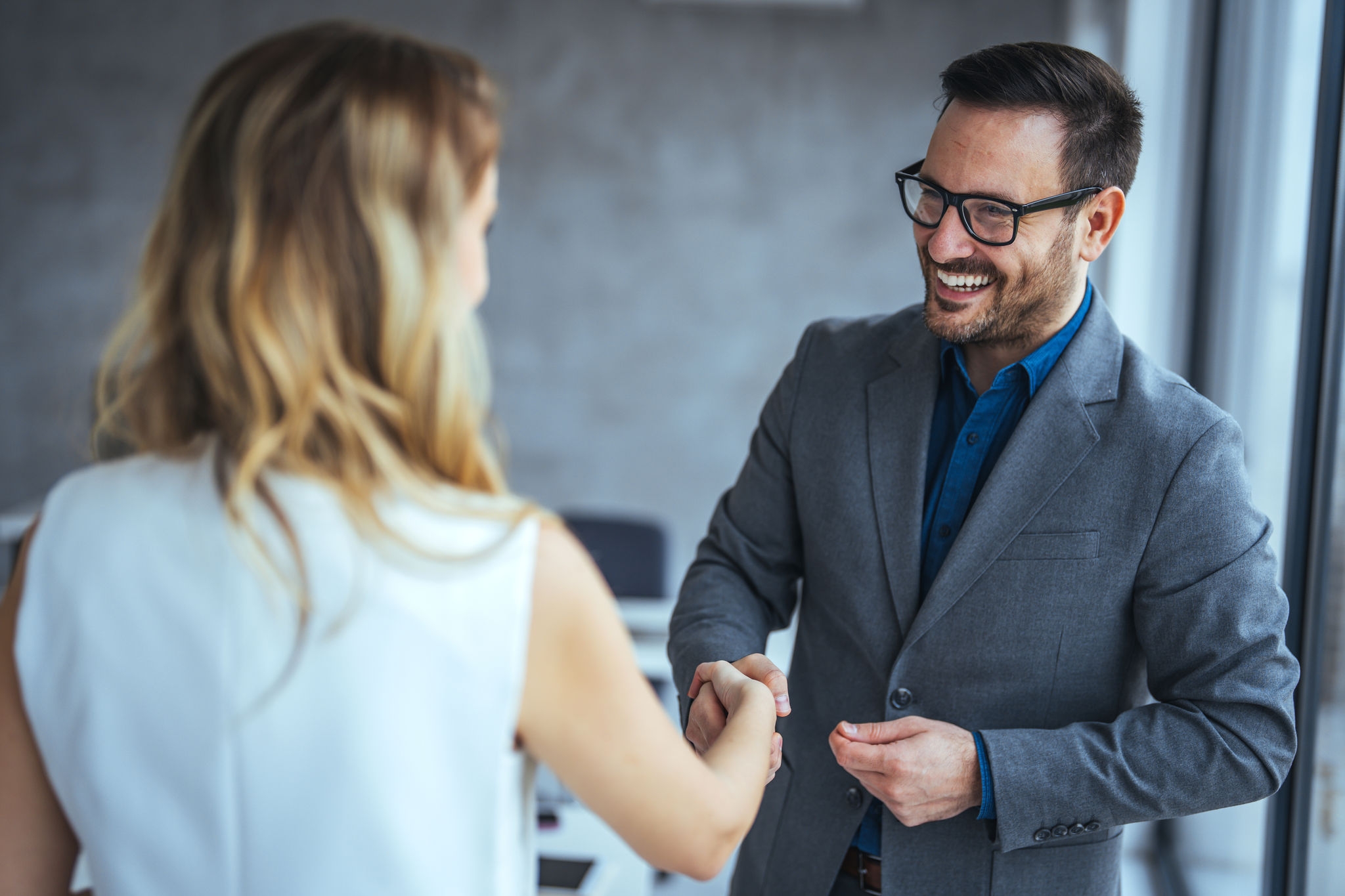 Portrait of cheerful young manager handshake with new employee. Close up of handshake in the office. Smiling businessman shaking hands while standing in an office. Handshake for the new agreement