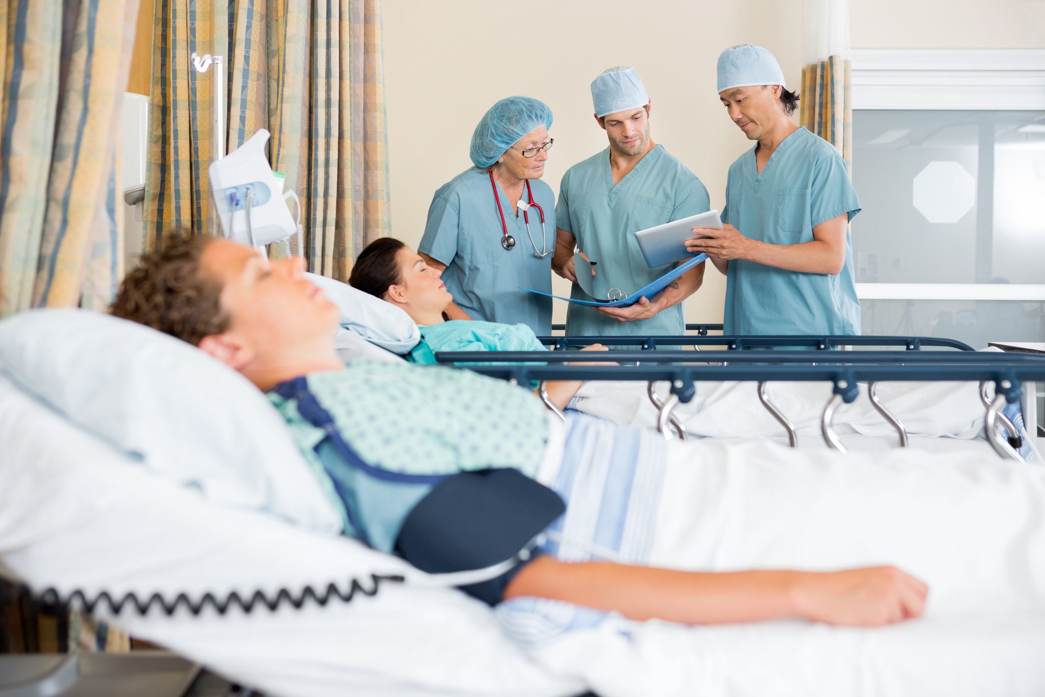 Team of nurses with digital tablet and file discussing patient's report in PACU