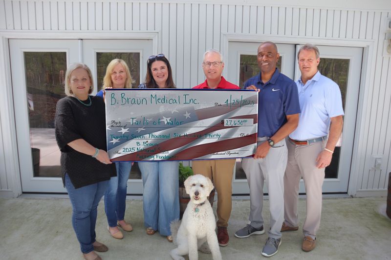 B. Braun team members and a Tails of Valor service dog at a presentation of funds raised during the 2025 National Sales Meeting.