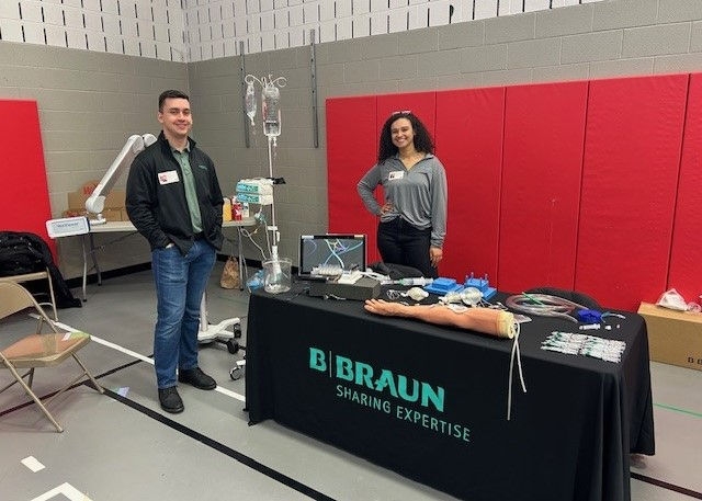 B. Braun team members at a STEAMM Expo booth showcasing the APEX® Compounding System and Clik-FIX® catheter securement device to students.