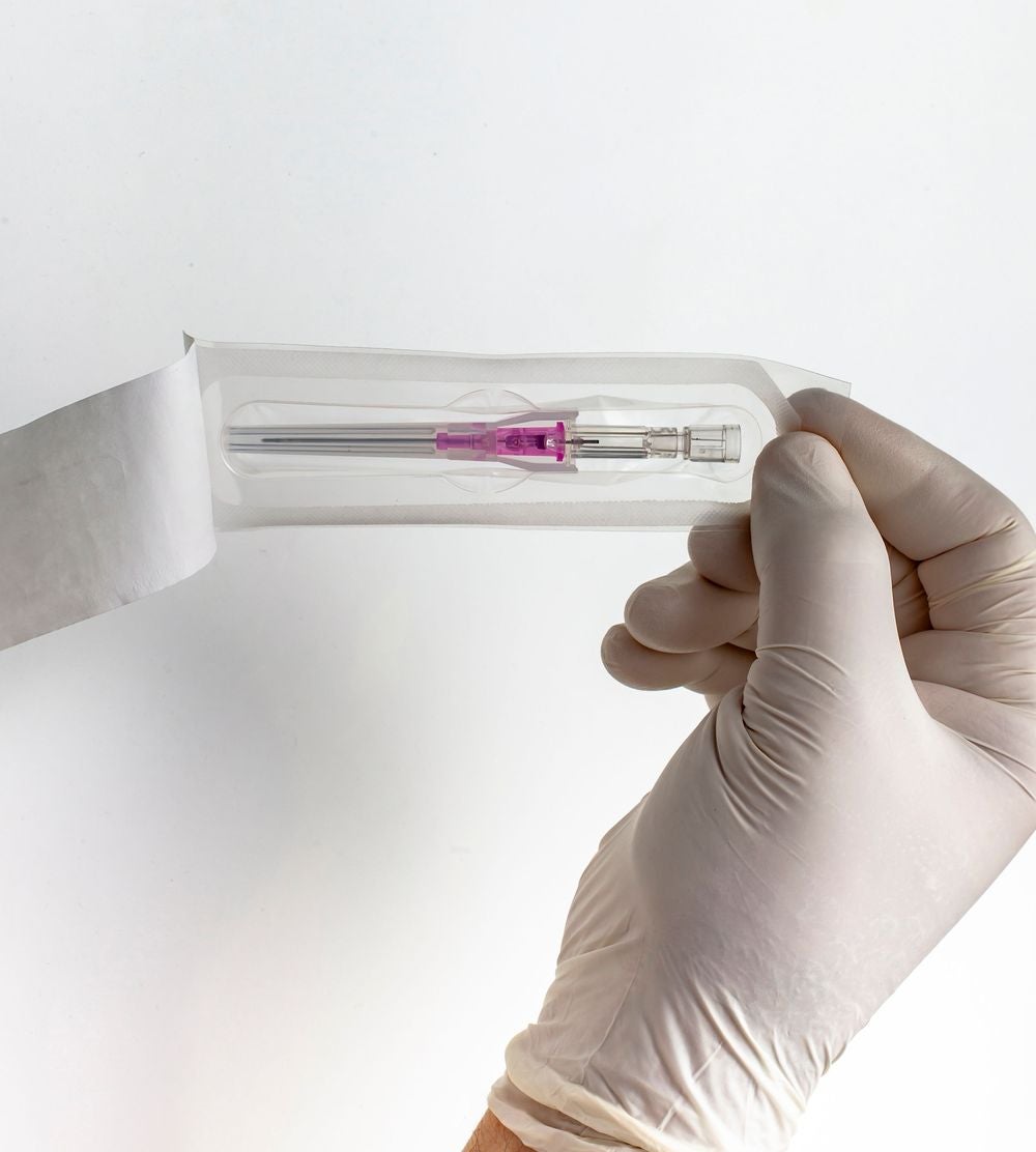 A gloved hand holding the Introcan Safety 2 IV Catheter open in its packaging.
