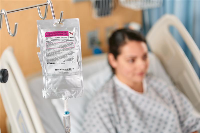 IV container with a patient lying in hospital bed.