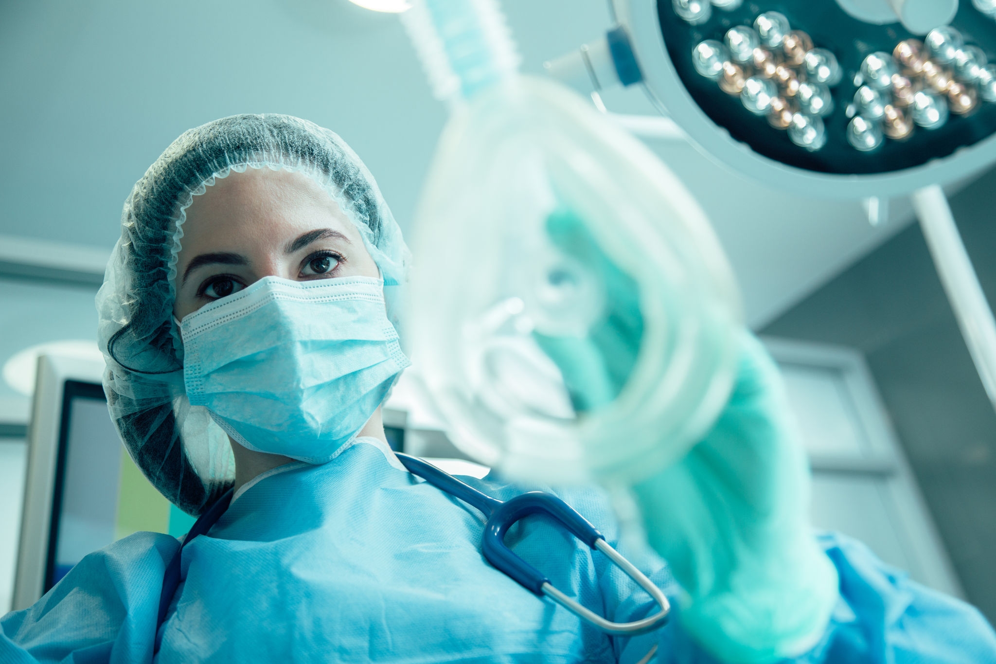 Woman in medical uniform standing with a mask for narcosis in her hand
