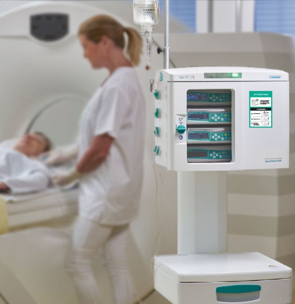A medical professional stands next to a patient who is lying in an MRI Suite with SpaceStation MRI.