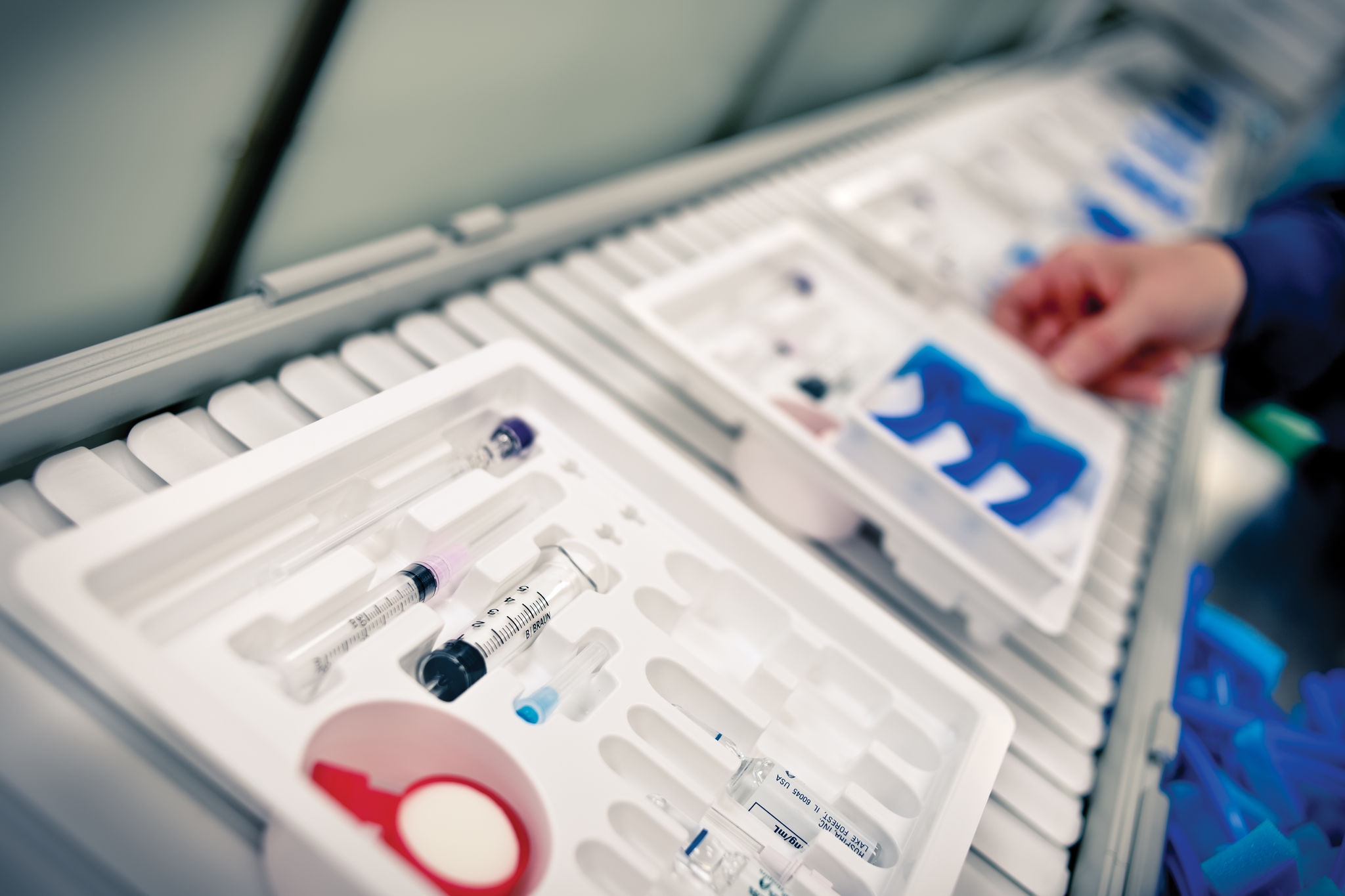 Procedure kits and solutions getting packaged into white trays. 
