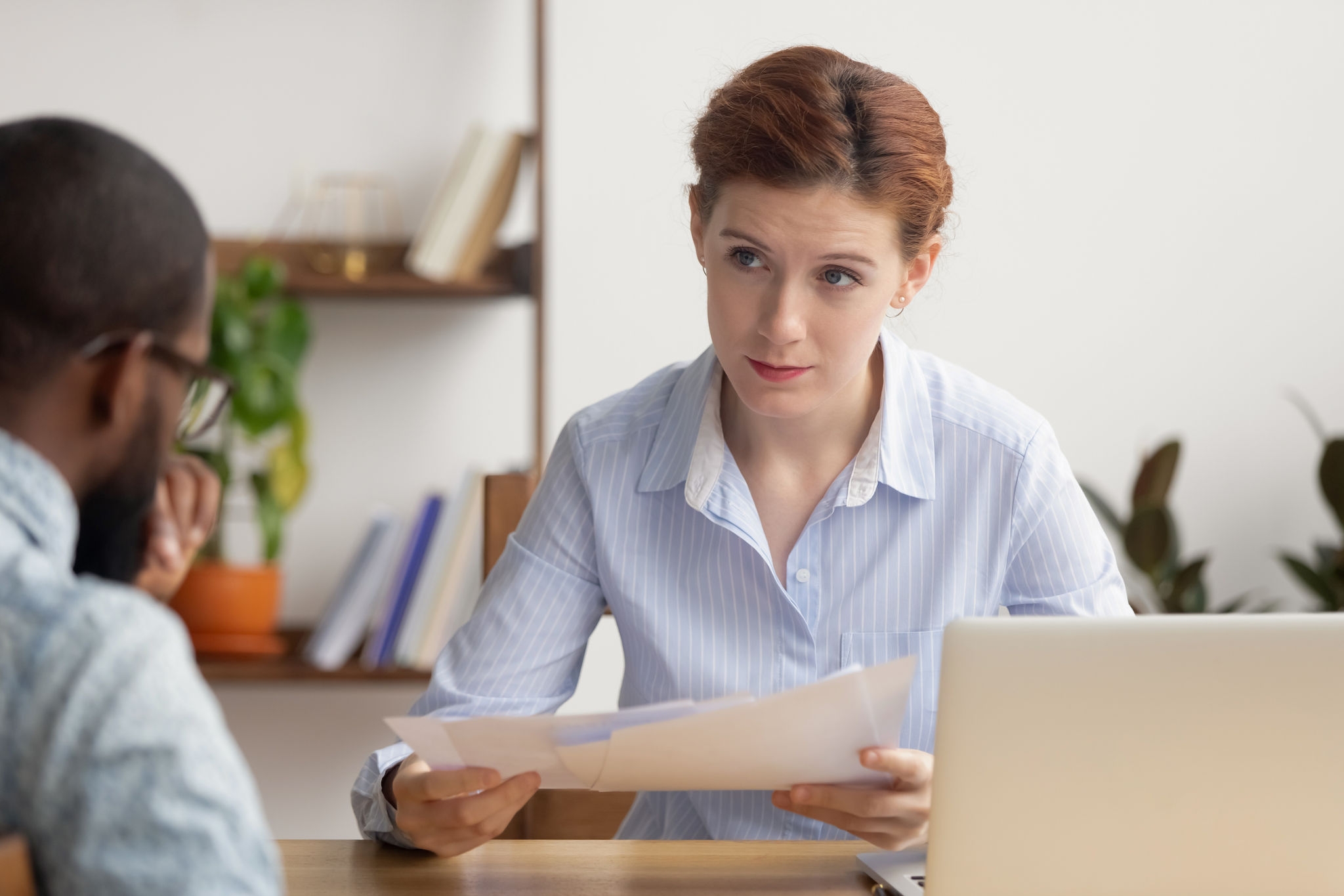 Angry female boss dissatisfied with bad financial result in report demand explanation from stressed incompetent african employee scolding upset intern for mistake in paperwork having conflict at work