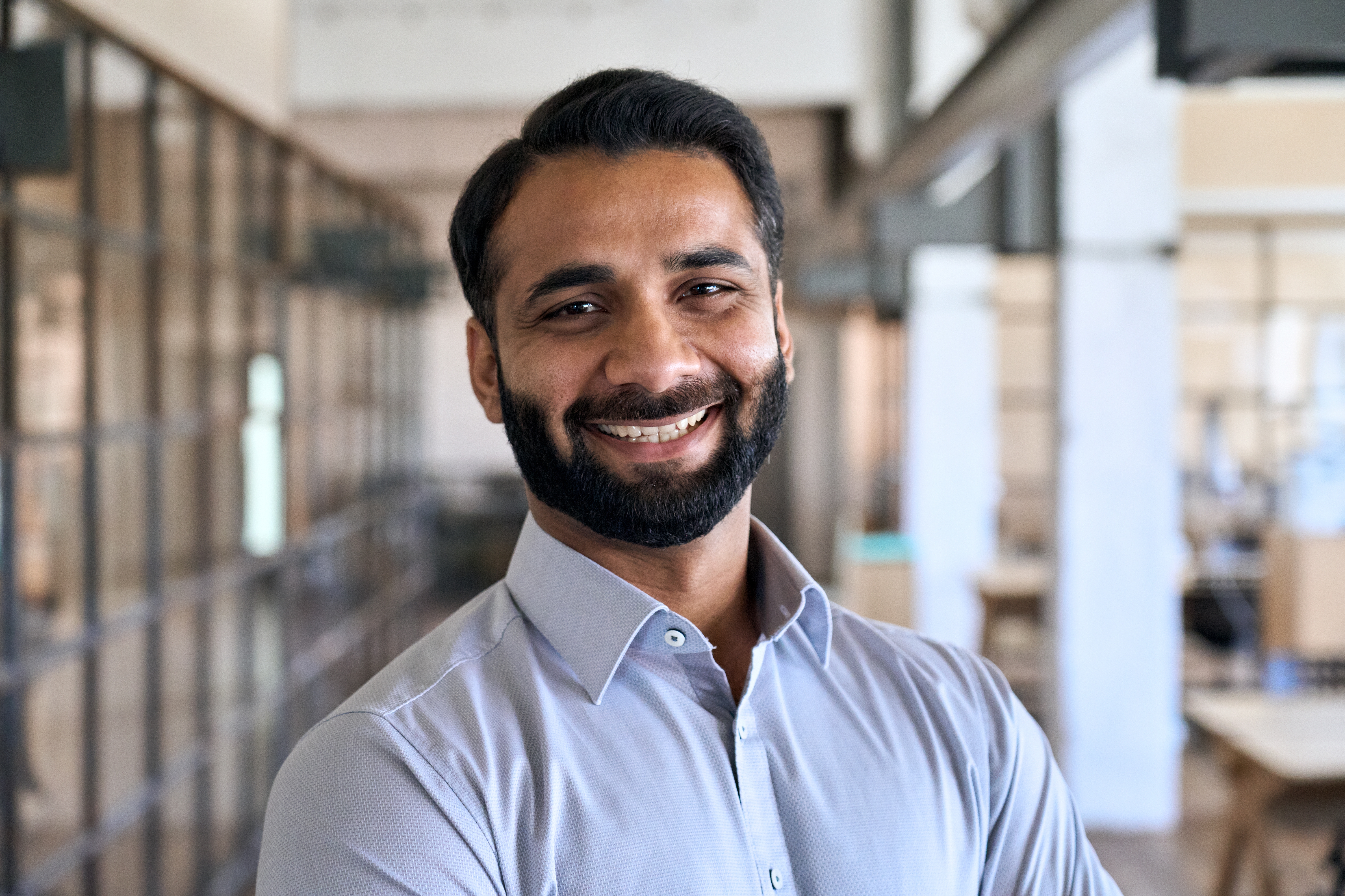 Close up portrait of a businessman smiling in a bright office setting.