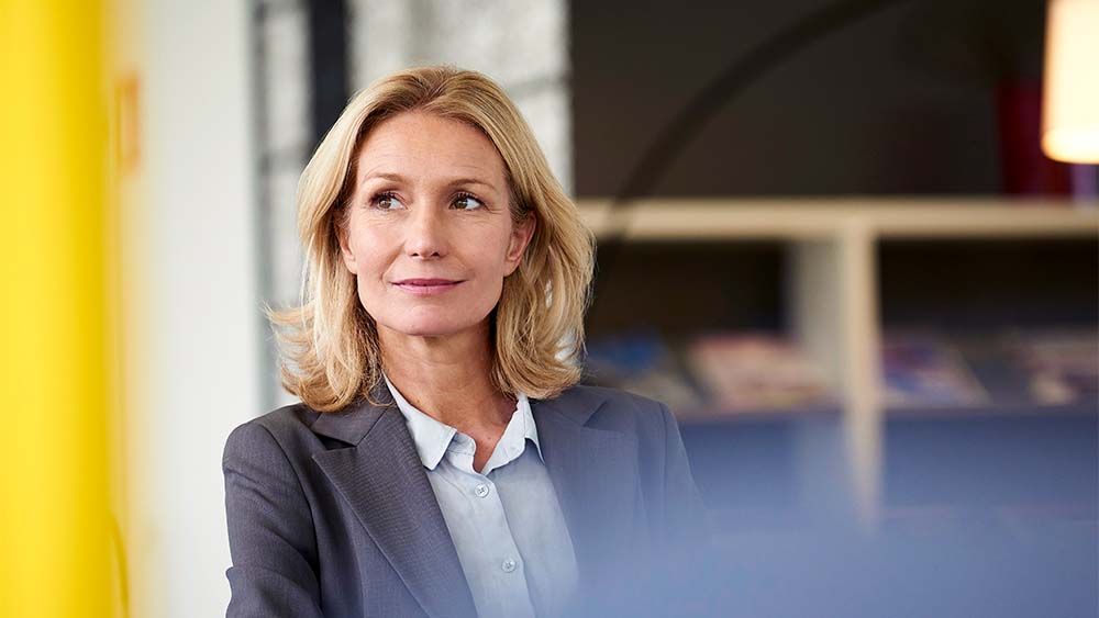 Professional woman looking off to the side with a slight smile in a workplace setting.