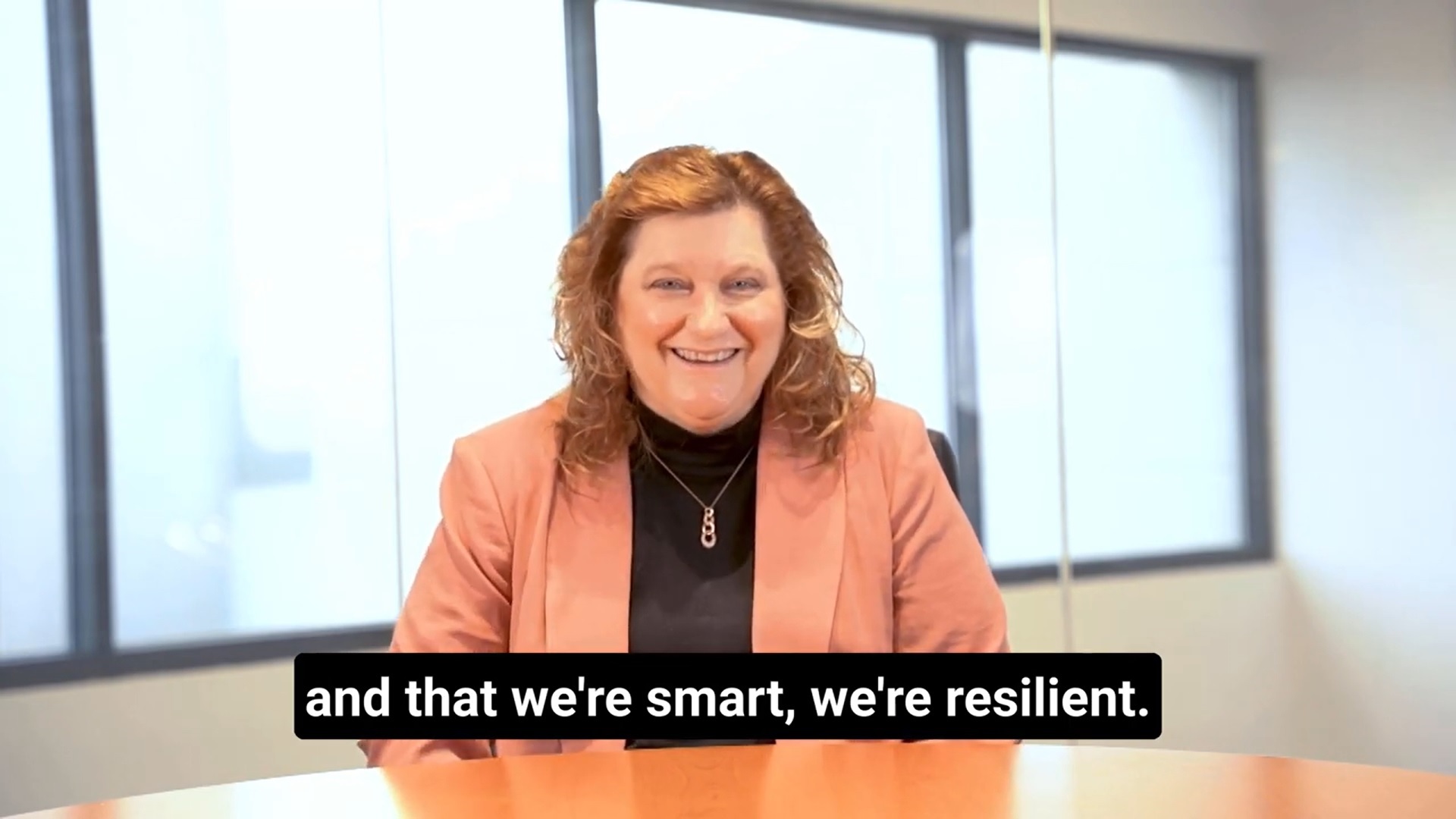 Employee and member of the Women's Employee Resource Group sitting in a conference room, smiling.