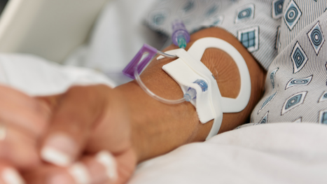A close-up of a Clik-FIX Securement Device on a patient's forearm. 