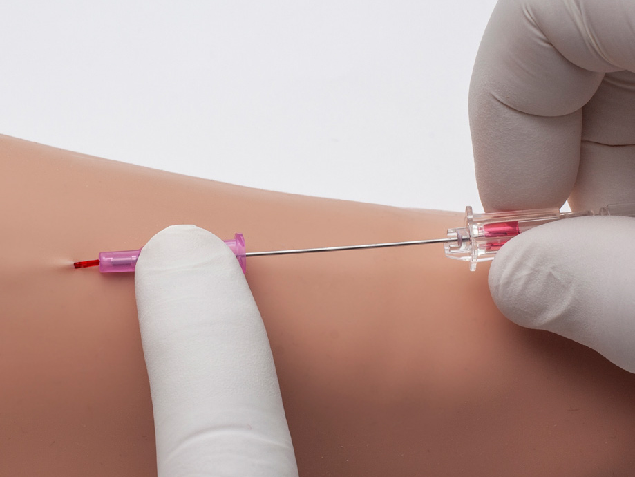 Close-up of the Introcan Safety 2 IV Catheter showcasing passive safety technology as one gloved finger holds it in place and another gloved hand inserts it into an arm. 