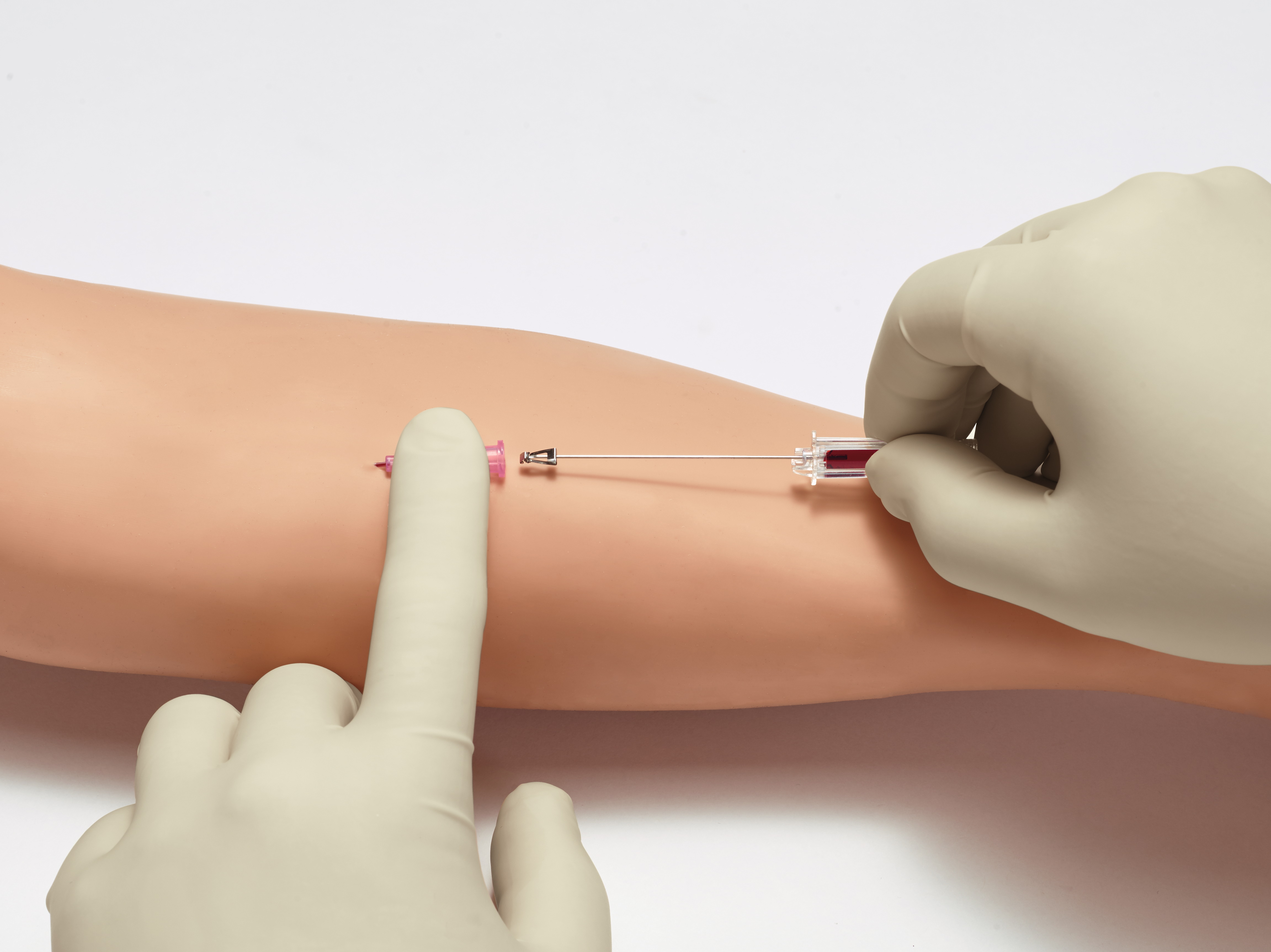 Introcan Safety 2 IV Catheter showcasing passive safety technology as one gloved finger holds it in place and another gloved hand inserts it into an arm.