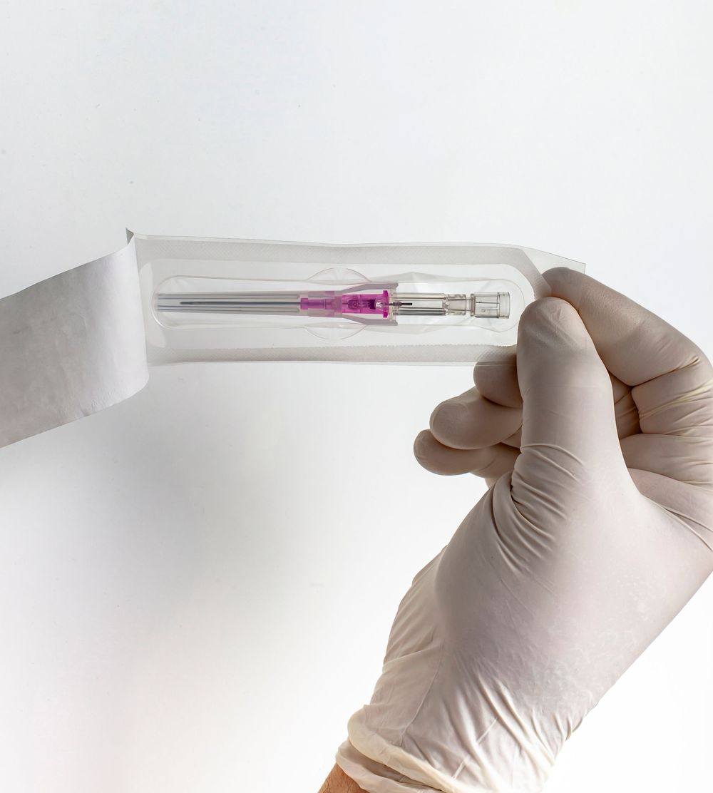 A gloved hand holding the Introcan Safety 2 IV Catheter open in its packaging.